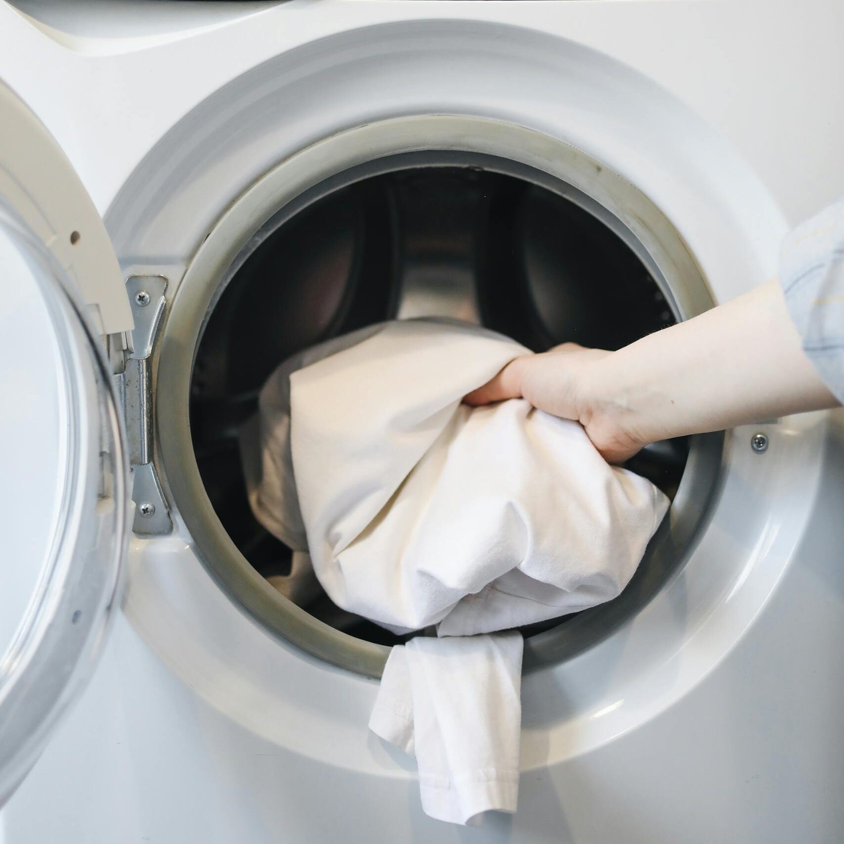 A Person Putting Clothes in a Washing Machine